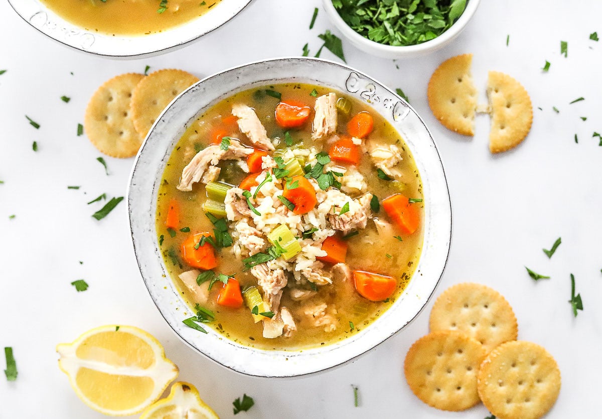 Turkey and rice soup in a bowl with crackers around it.