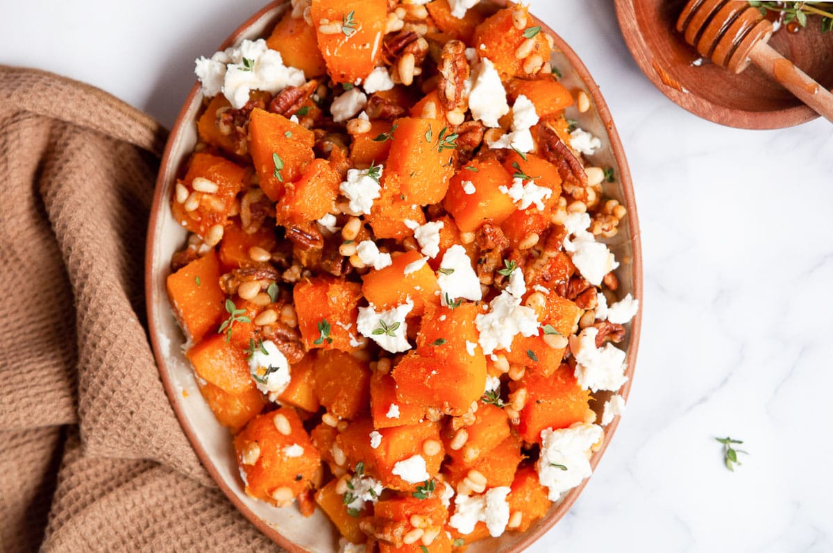 Sauteed butternut squash with goat cheese in a bowl and linen towel near.