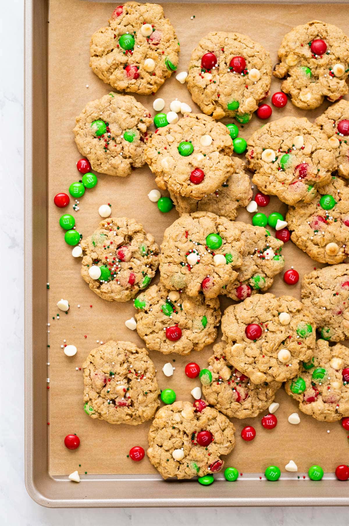 Christmas monster cookies with holiday m&m's and white chocolate chips on baking tray.