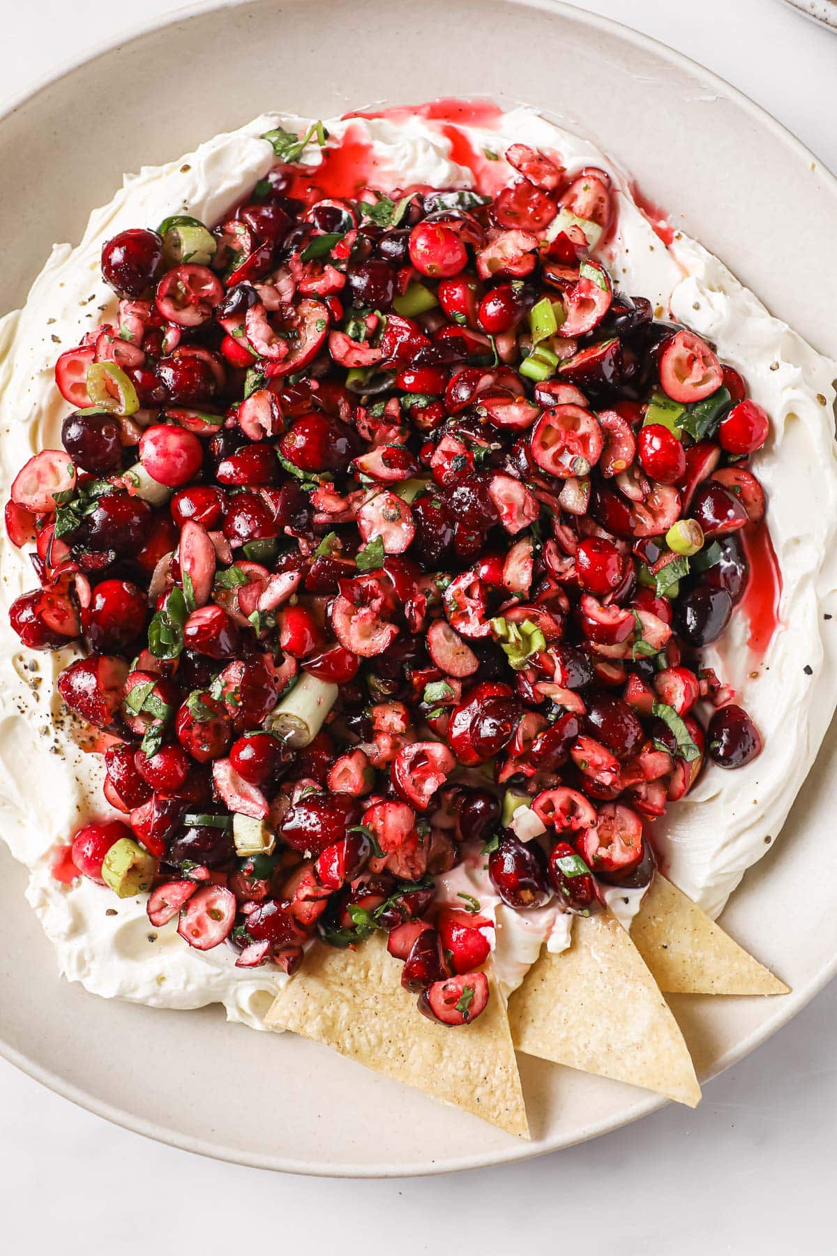 Cranberry jalapeno dip with cream cheese served in a bowl with tortilla chips.