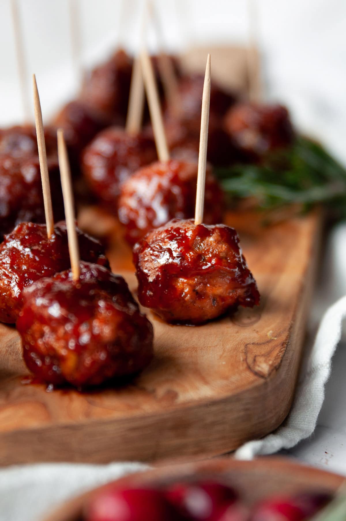 Cranberry meatballs with toothpicks on a wooden board.