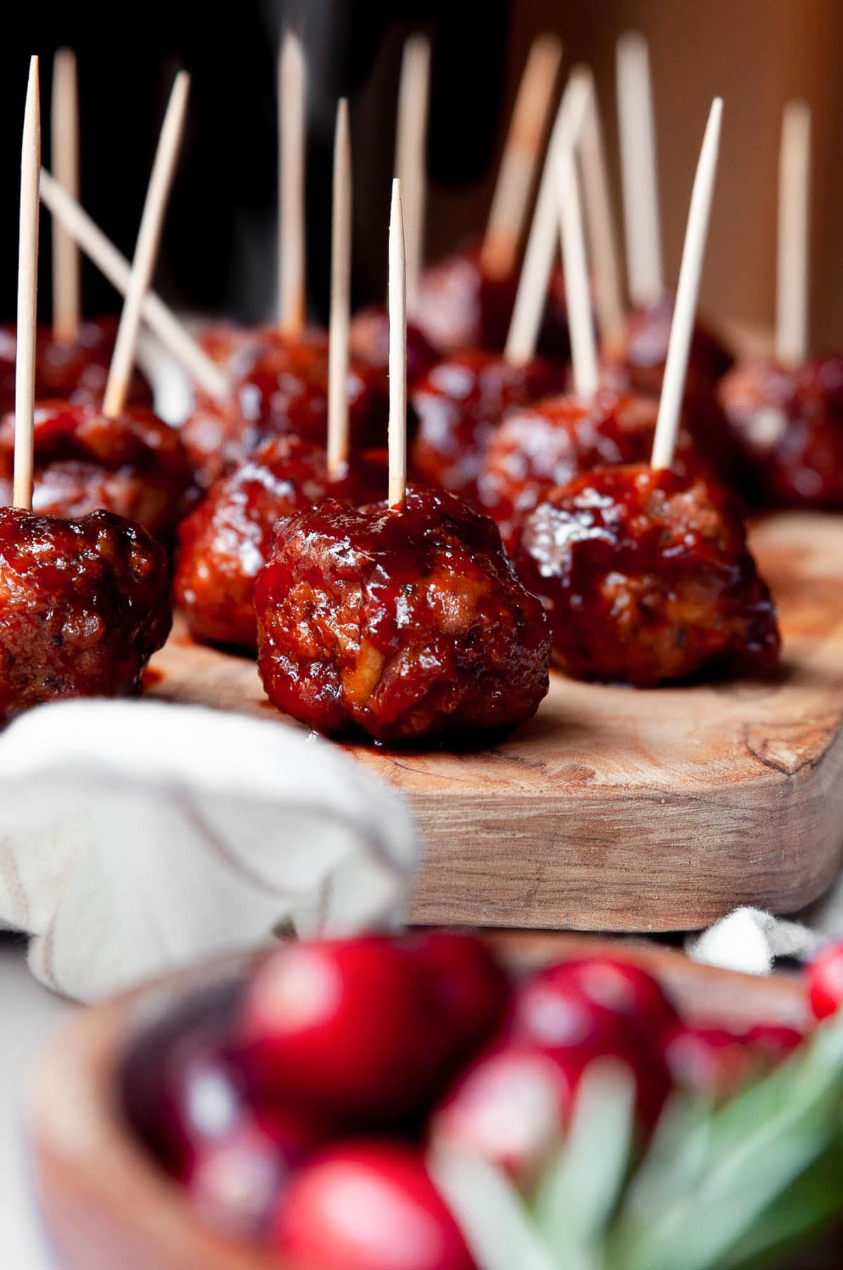 Cranberry turkey meatballs served with inserted toothpicks on a wooden board.