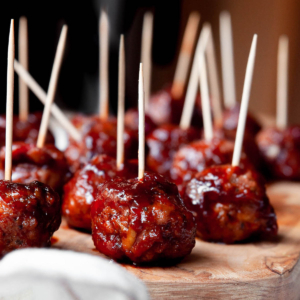 Cranberry turkey meatballs served with inserted toothpicks on a wooden board.