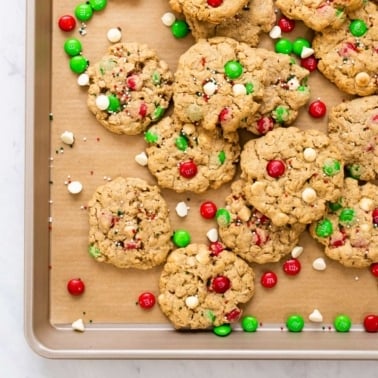 Christmas monster cookies with holiday m&m's and white chocolate chips on baking tray.