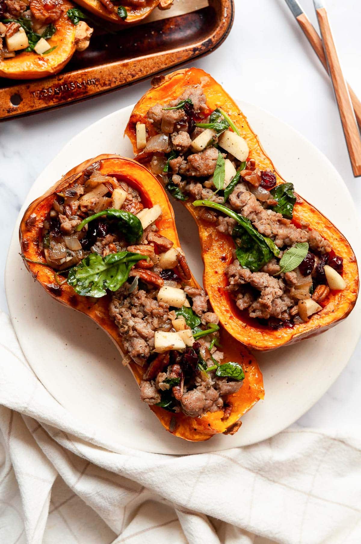 Two roasted butternut squash halves stuffed with apple sausage filling.