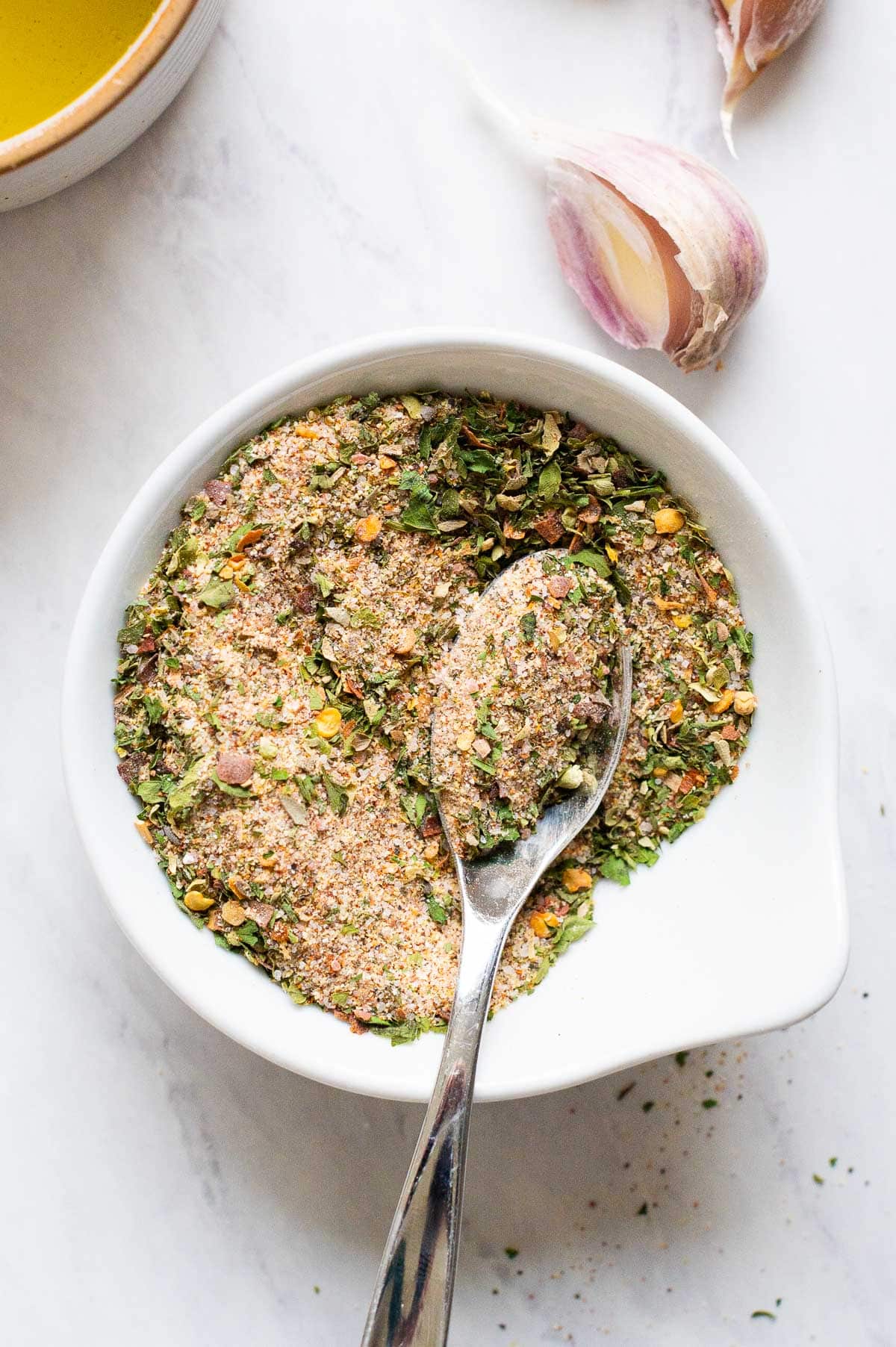 All purpose seasoning in white bowl with a spoon.