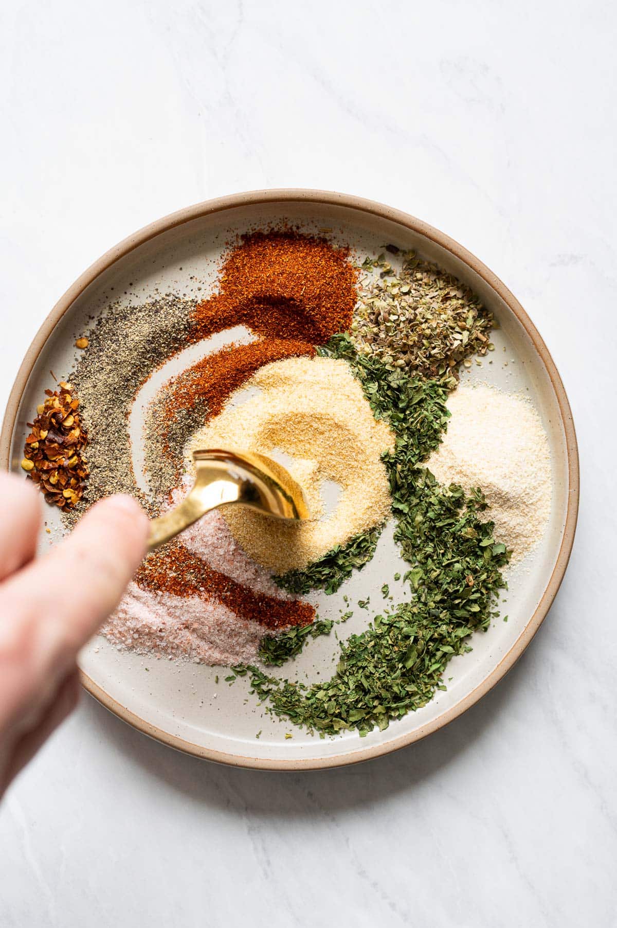 Person stirring spices on a plate.