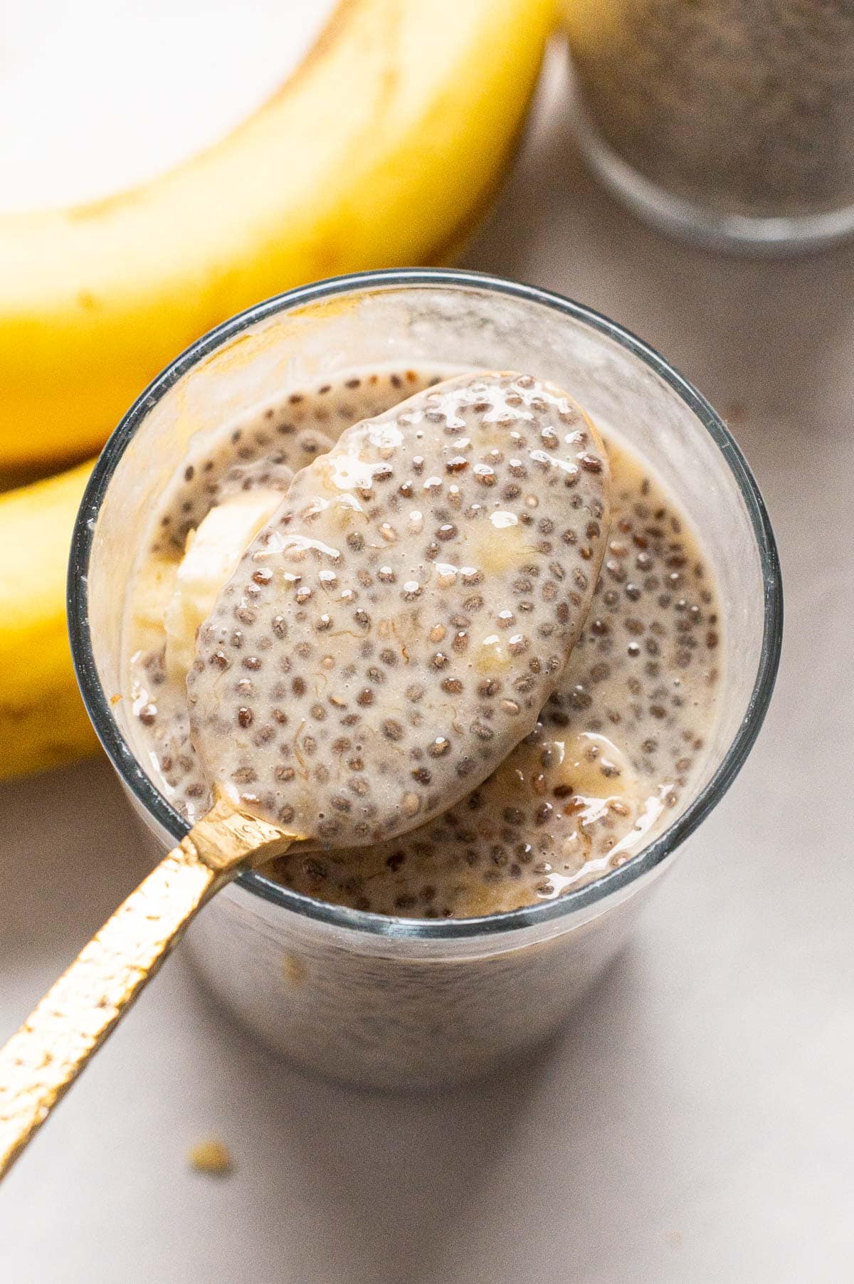 Close up off banana chia pudding on a spoon above the jar.