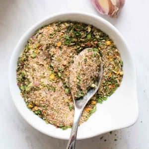 All purpose seasoning in white bowl with a spoon.