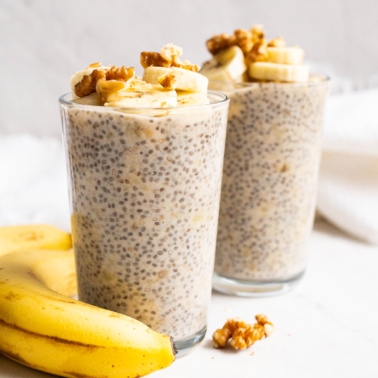 Banana chia pudding topped with sliced bananas and walnuts served in glasses.