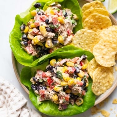 Mexican tuna salad served in lettuce leaves with tortilla chips on a plate.