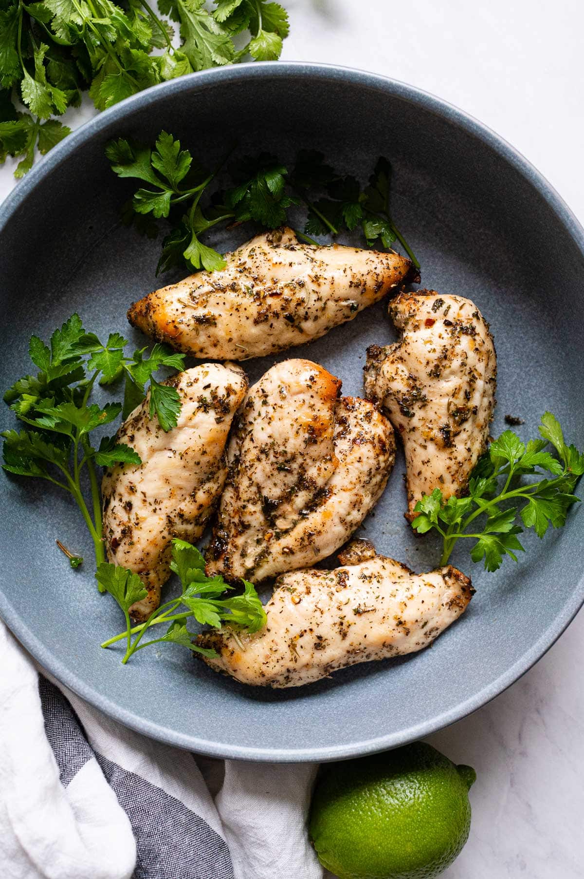 Air fryer frozen chicken breasts with parsley on a blue plate.