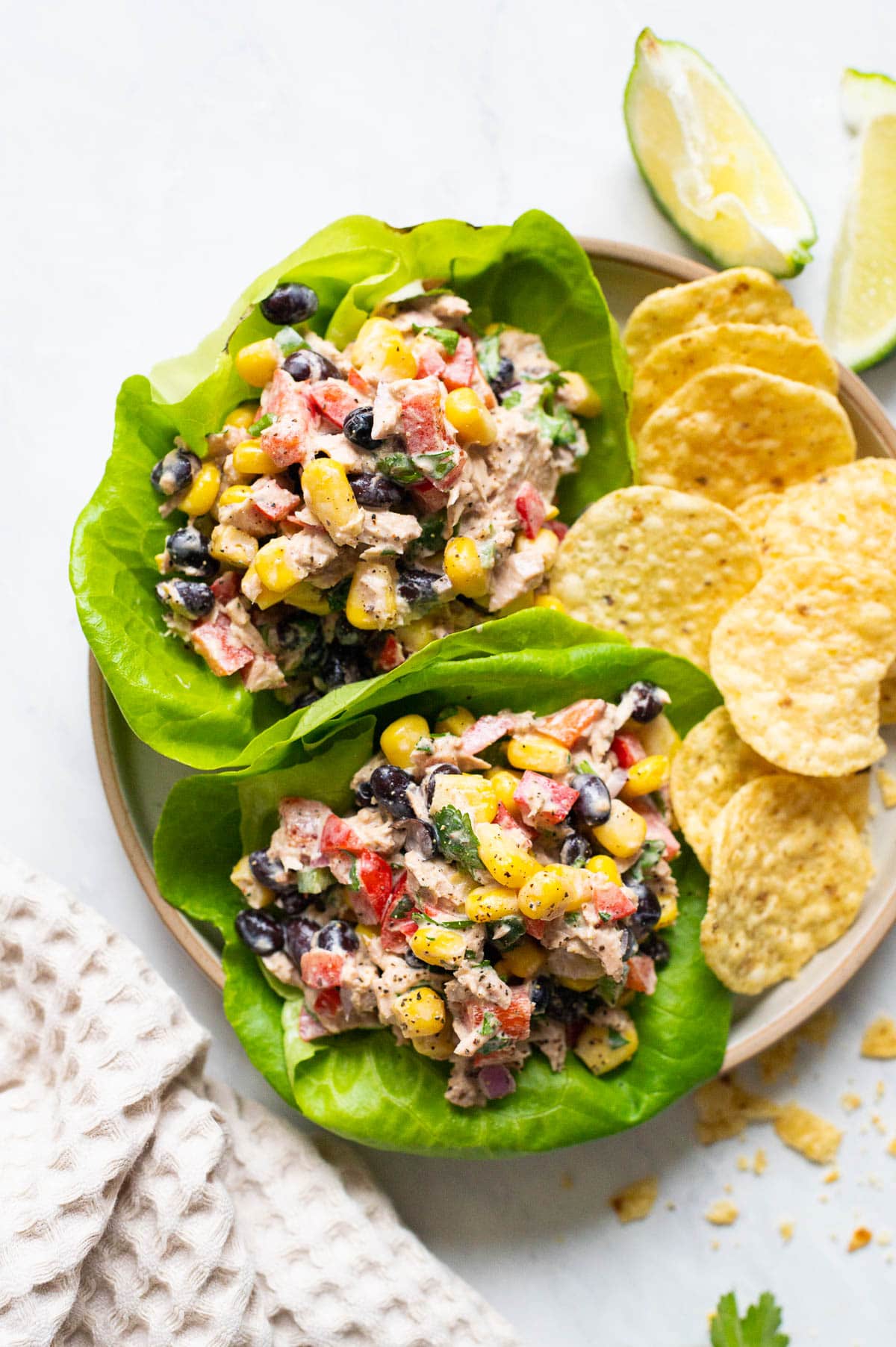 Mexican tuna salad served in lettuce leaves with tortilla chips on a plate.