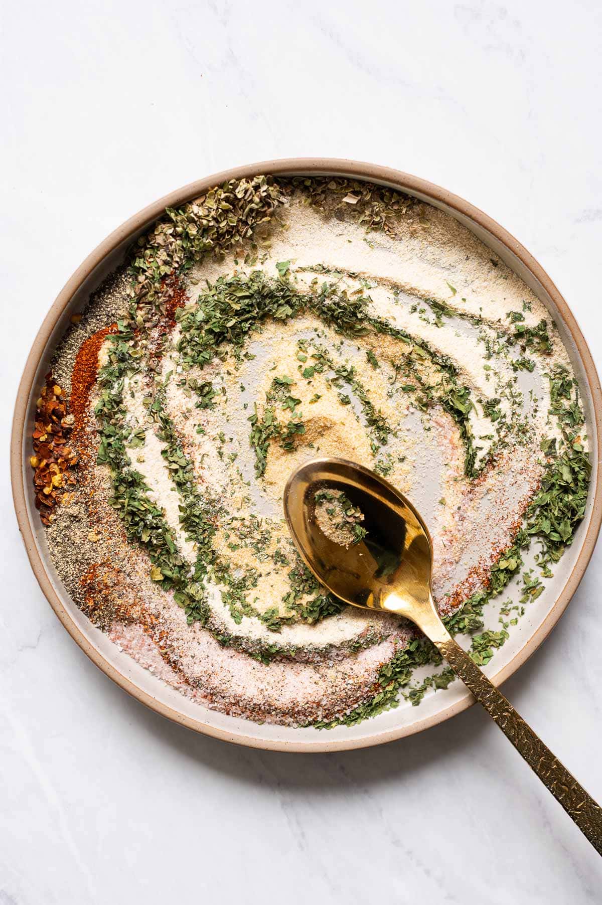 All purpose seasoning blend stirred on a plate with a spoon.