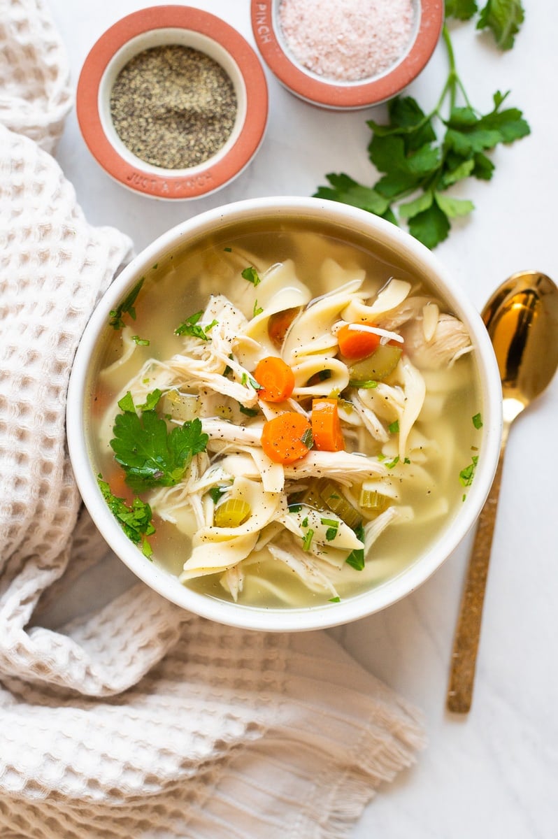 Crockpot chicken noodle soup with carrots and celery served in a bowl garnished with parsley.