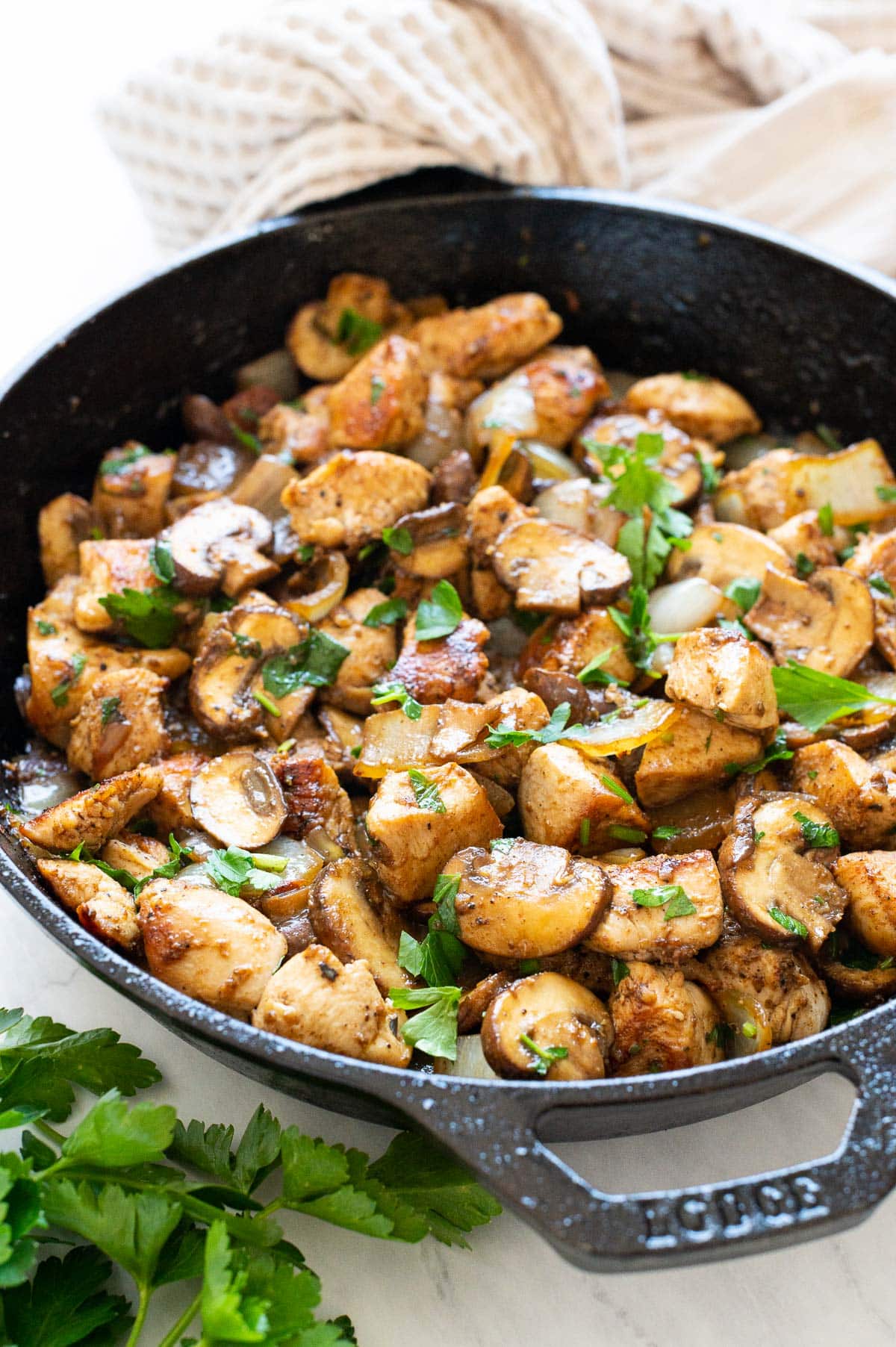 Sauteed chicken and mushrooms in cast iron skillet garnished with parsley.