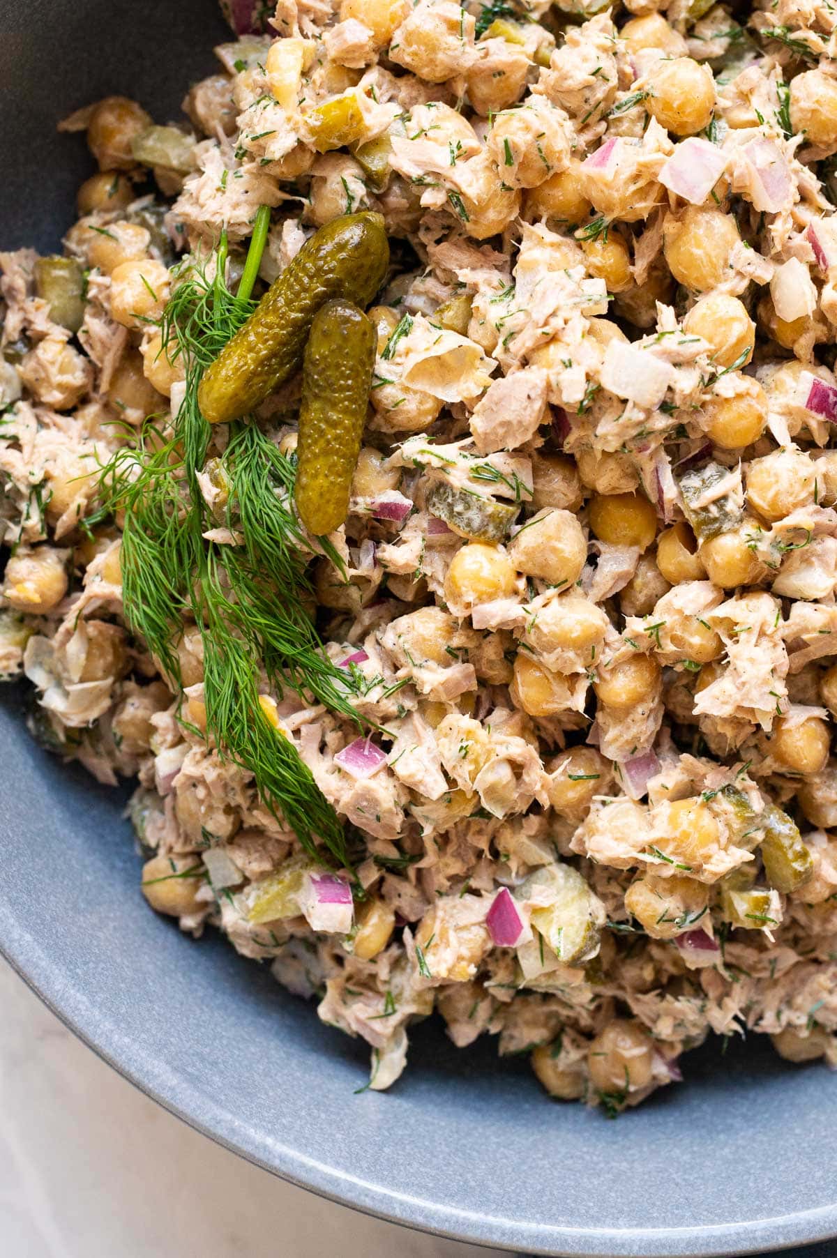 Close up of chickpea salad with tuna, red onion, dill and pickles.