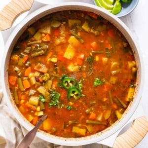 Mexican vegetable soup with jalapenos and cilantro in a pot with ladle.