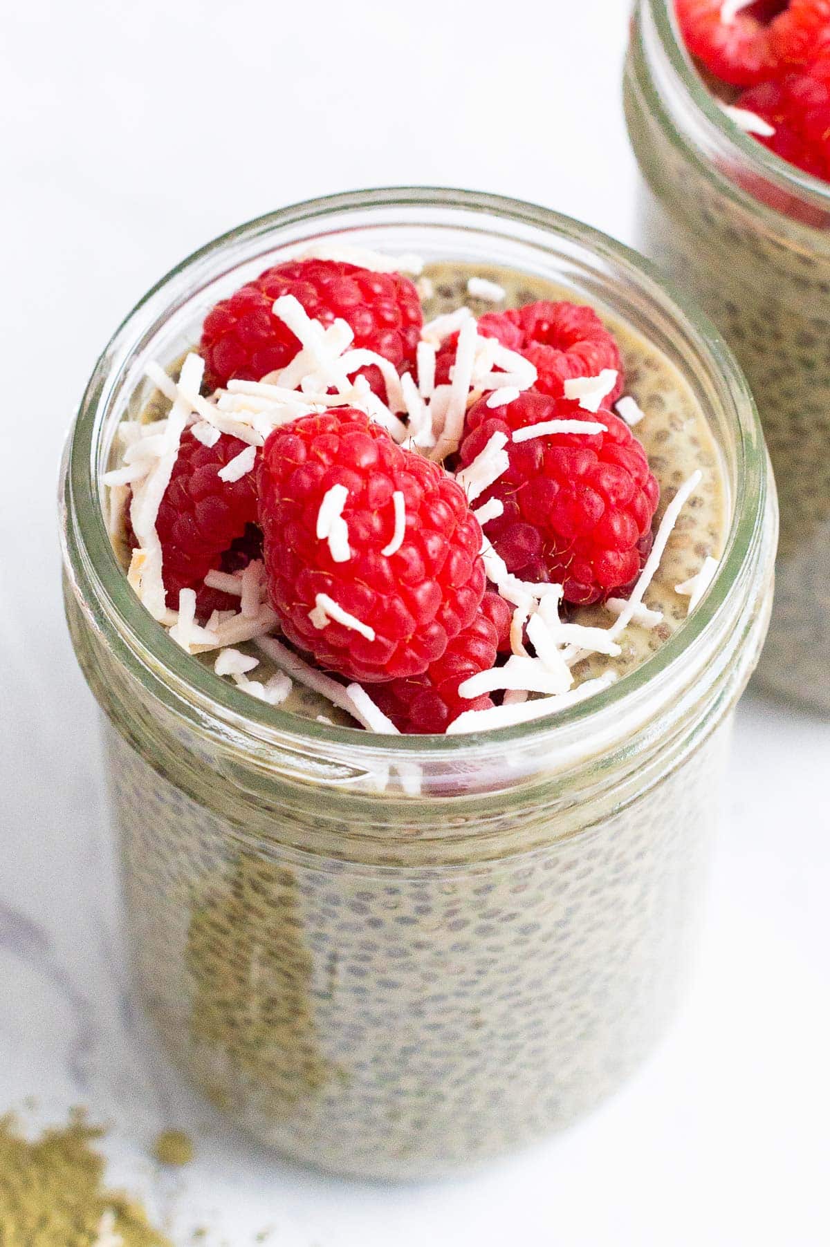 Close up of chia pudding topped with raspberries and coconut flakes.