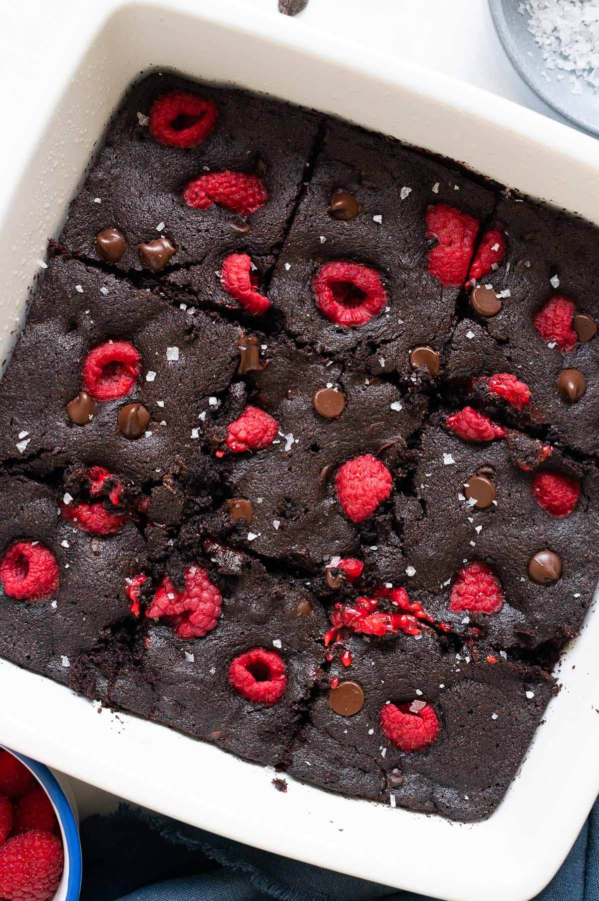Close up off brownies with raspberries, chocolate chips and sprinkled with sea salt flakes.