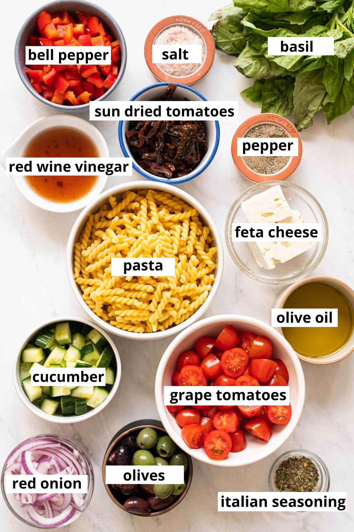 Pasta, sun-dried tomatoes, bell pepper, basil, grape tomatoes, cucumber, red onion, olives, Italian seasoning, olive oil, feta, vinegar, salt and pepper.