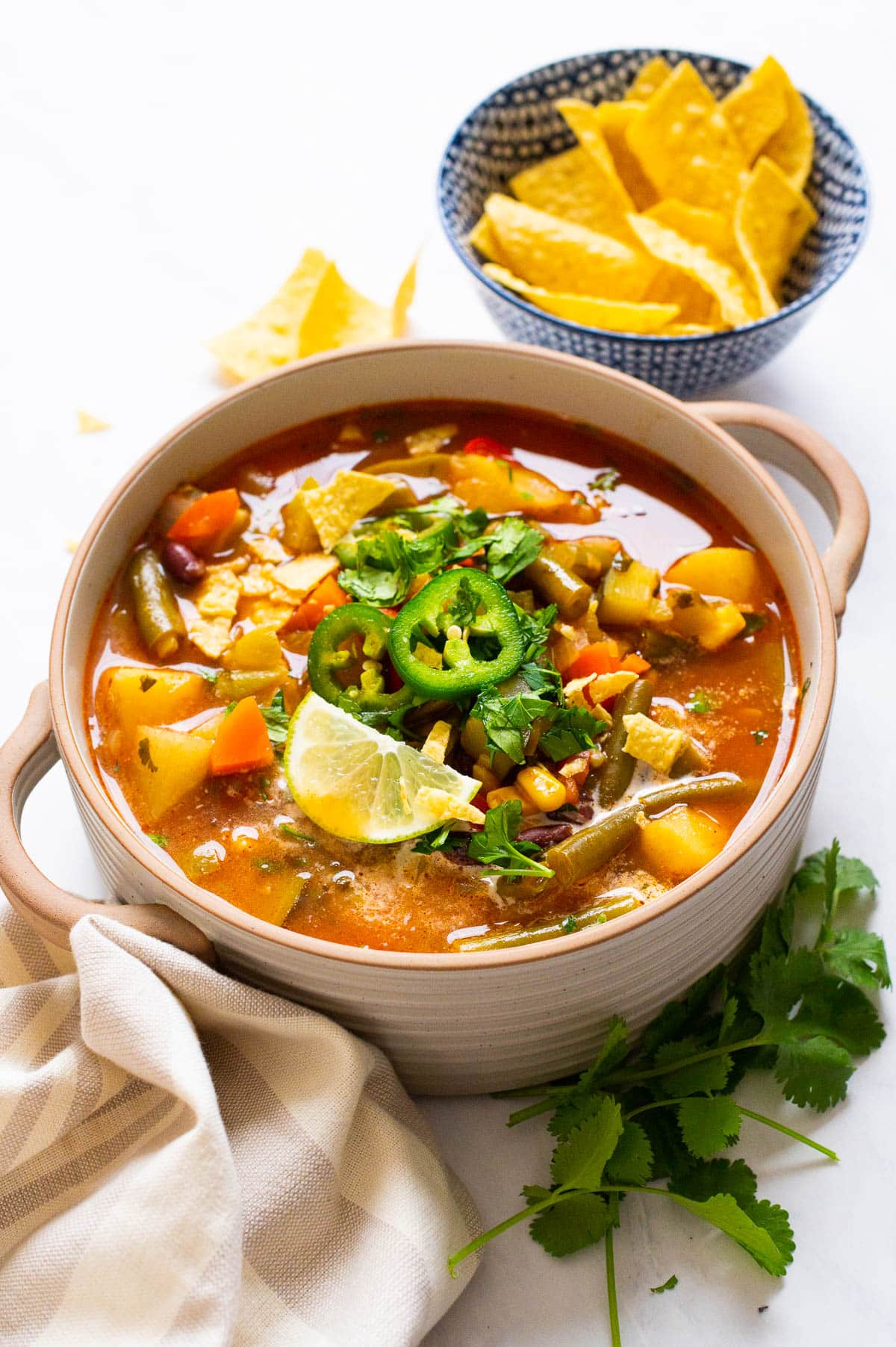 Mexican vegetables soup served in a bowl garnish with jalapenos, cilantro and lime.