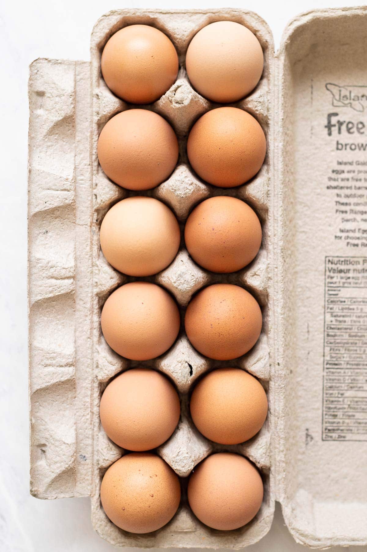 A dozen of brown eggs in a carton.