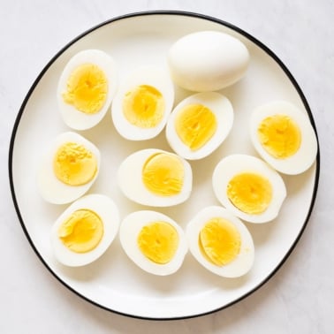 Sliced in half hard boiled eggs on white plate.