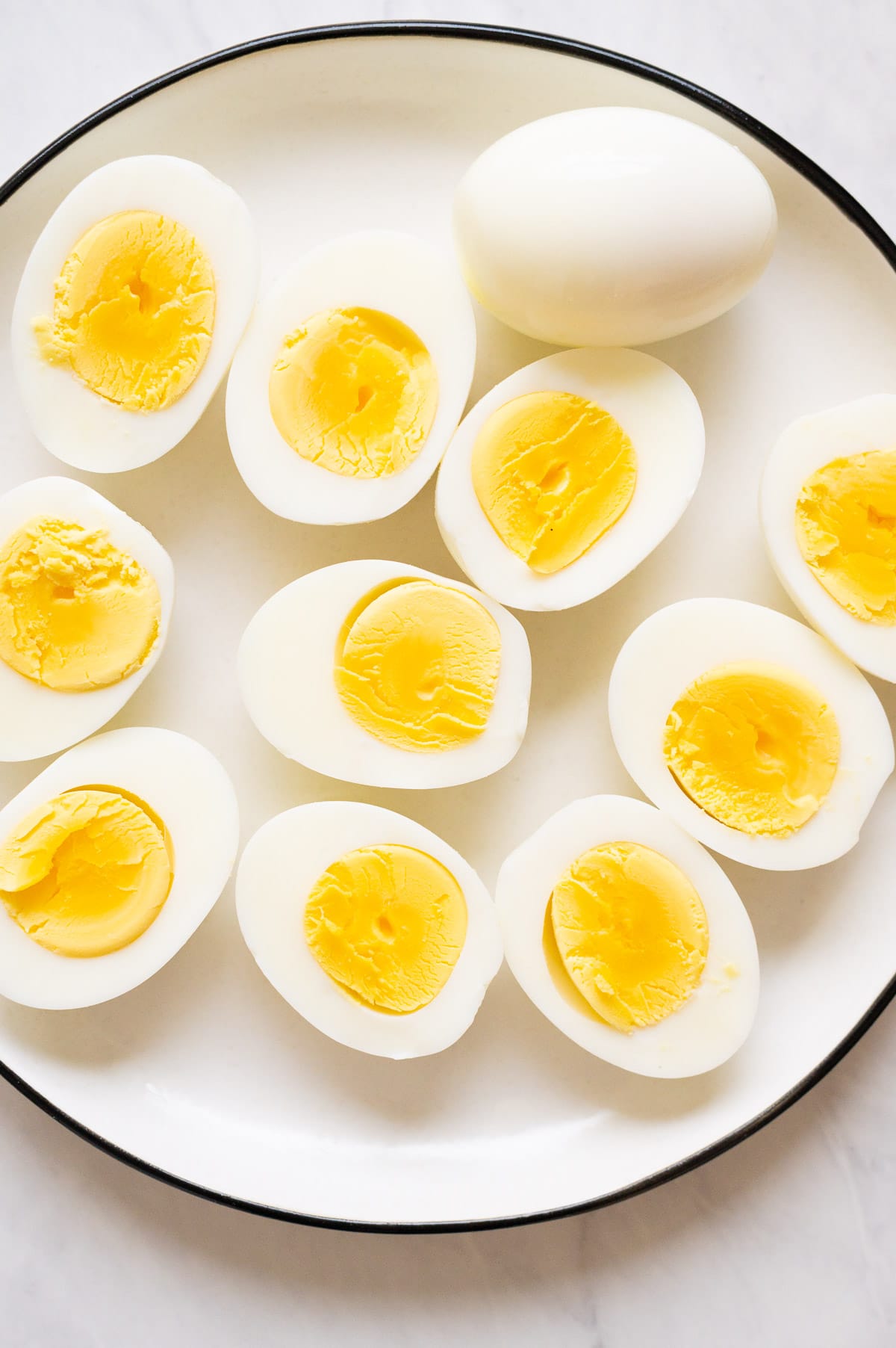 Sliced in half hard boiled eggs on white plate.