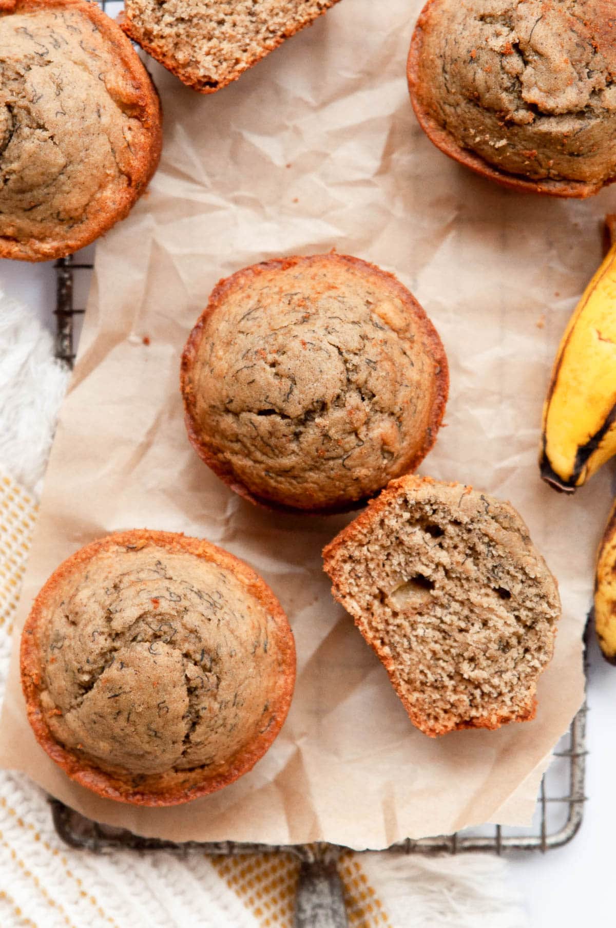 Two oat flour banana muffins and one sliced on parchment paper.