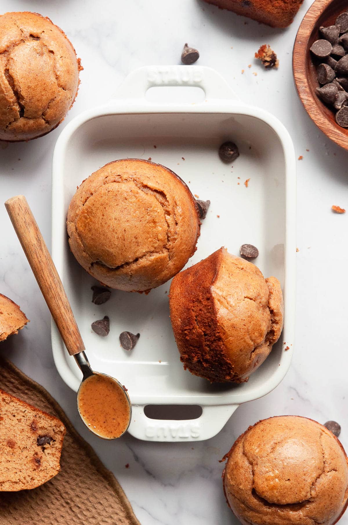 Protein muffins in a baking dish with chocolate chips and nut butter in a spoon.