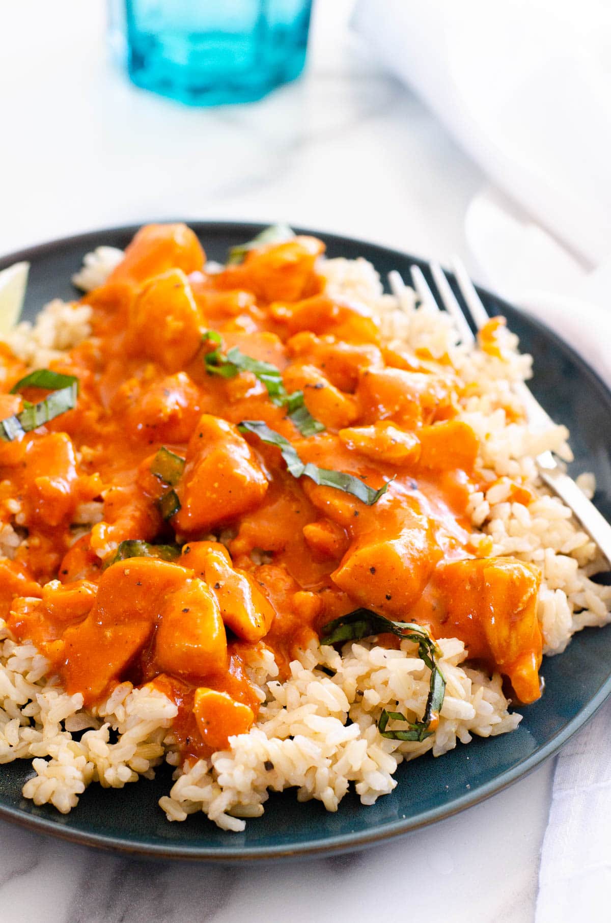 Thai chicken curry recipe served on a bed of brown rice and garnished with basil.