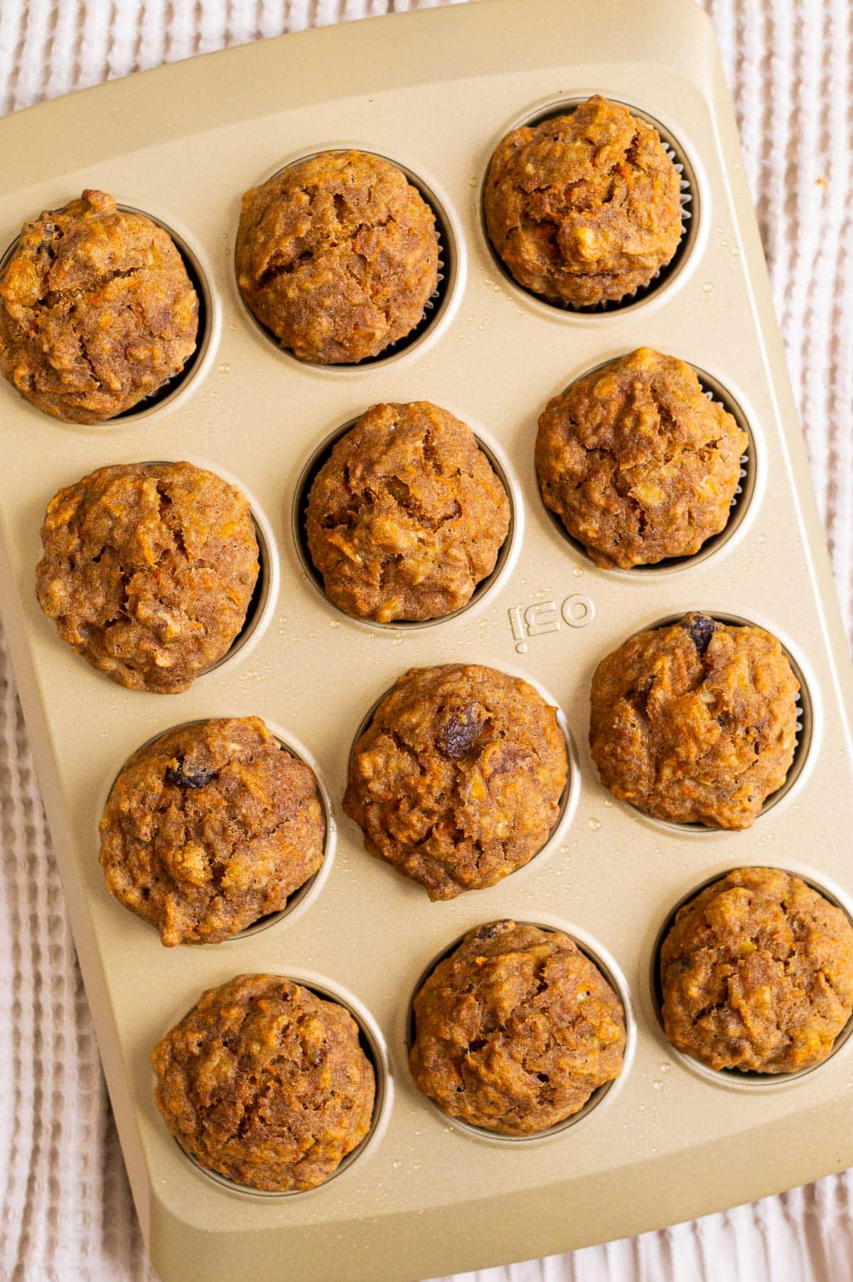 Top view of carrot banana muffins in a gold baking muffin tin.