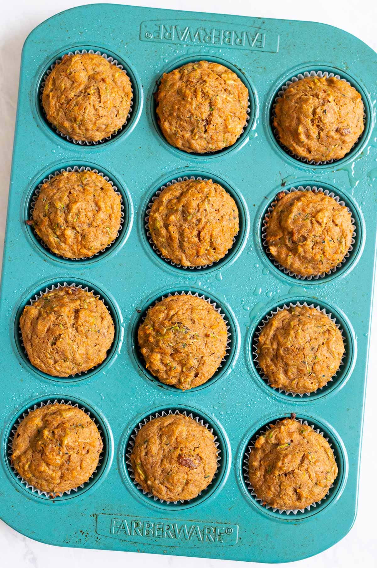 Carrot zucchini muffins in blue muffin tin.
