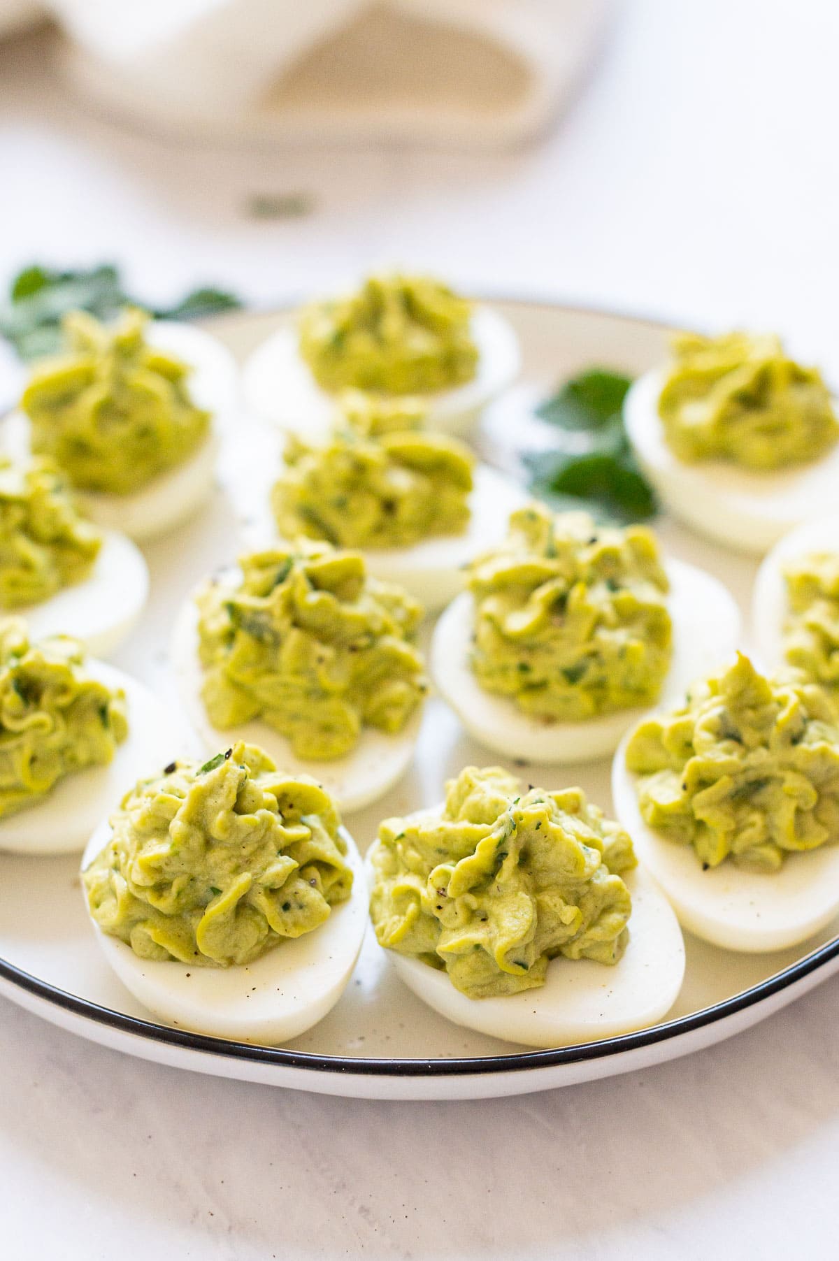 Side view of deviled eggs with avocado on a plate.