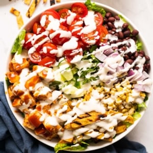 Bbq chicken salad drizzled with ranch dressing in a bowl.