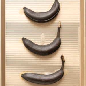 Three brown overripe bananas on a baking sheet.