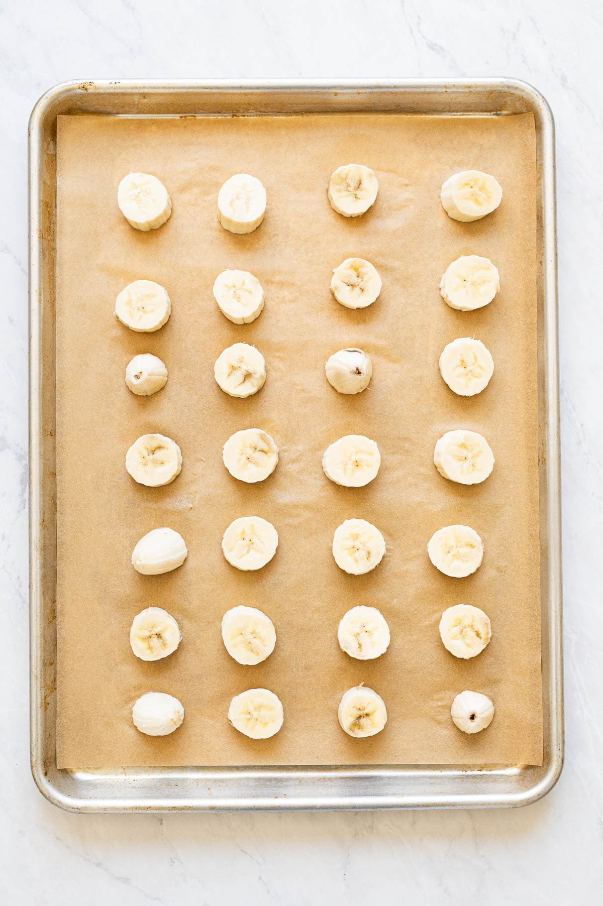 Banana slices on baking sheet lined with parchment paper.
