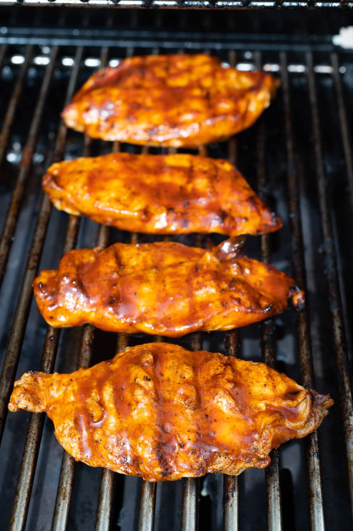 Grilled barbecue chicken breasts on a grill.