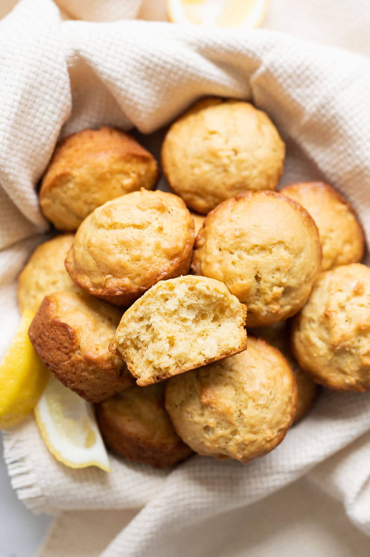 Close up photo showing texture of inside of a lemon muffin in a basket with other lemon muffins.