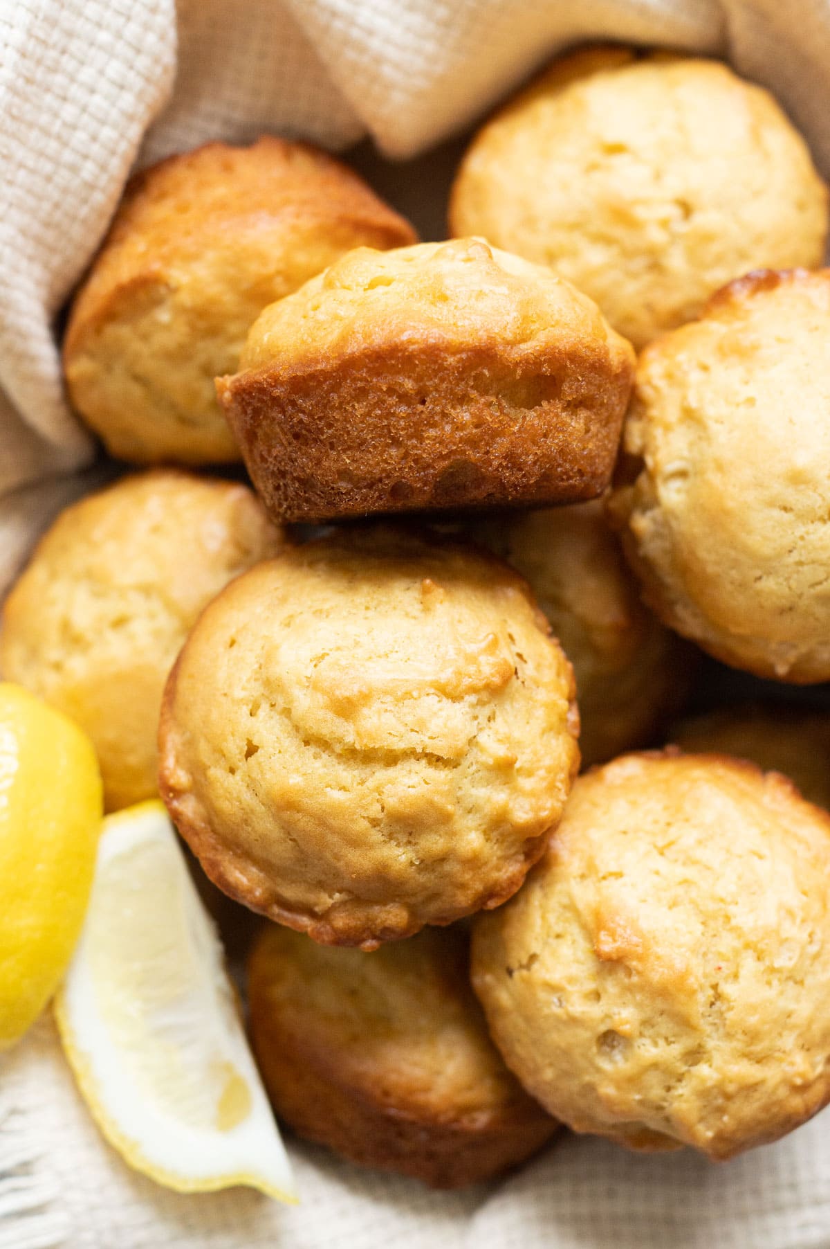Lemon muffins served in a basket with a few slices of fresh lemon.
