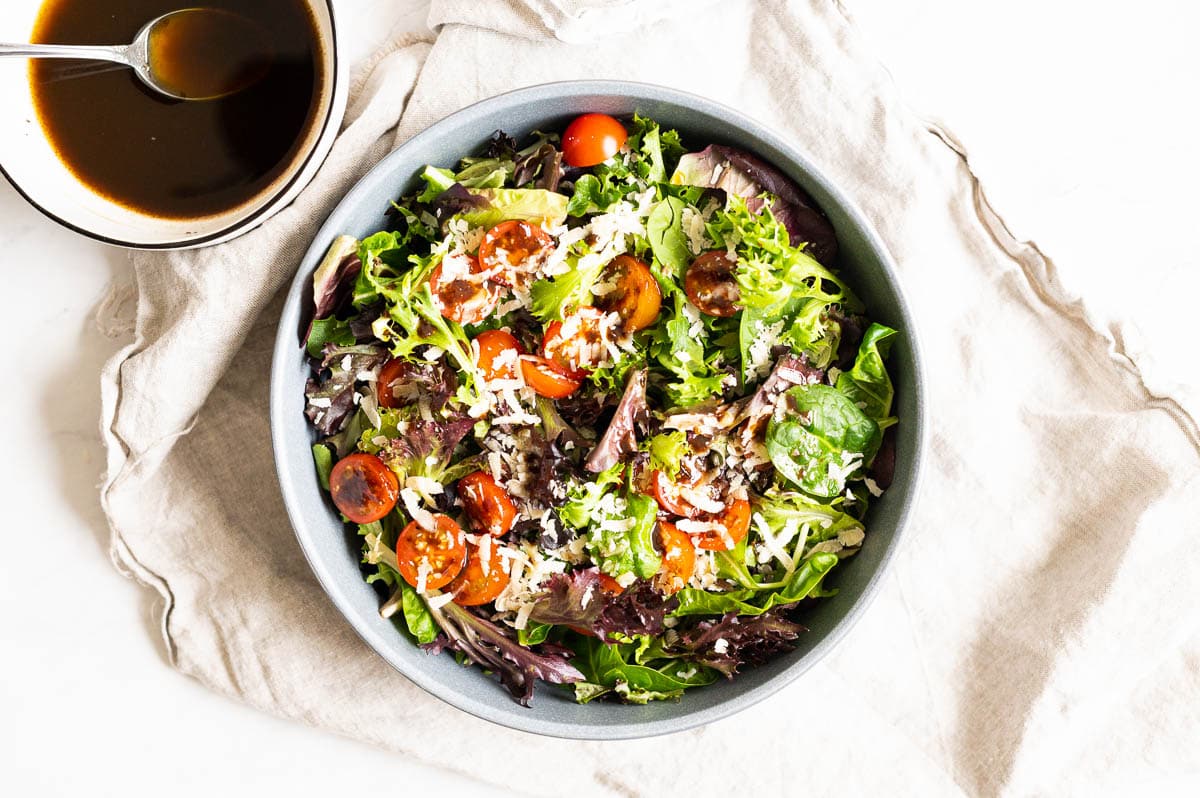A bowl with mixed greens salad and balsamic vinaigrette in another bowl.
