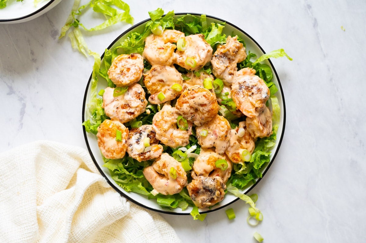 Bang Bang Shrimp served on a bed of lettuce and sprinkled with green onions.