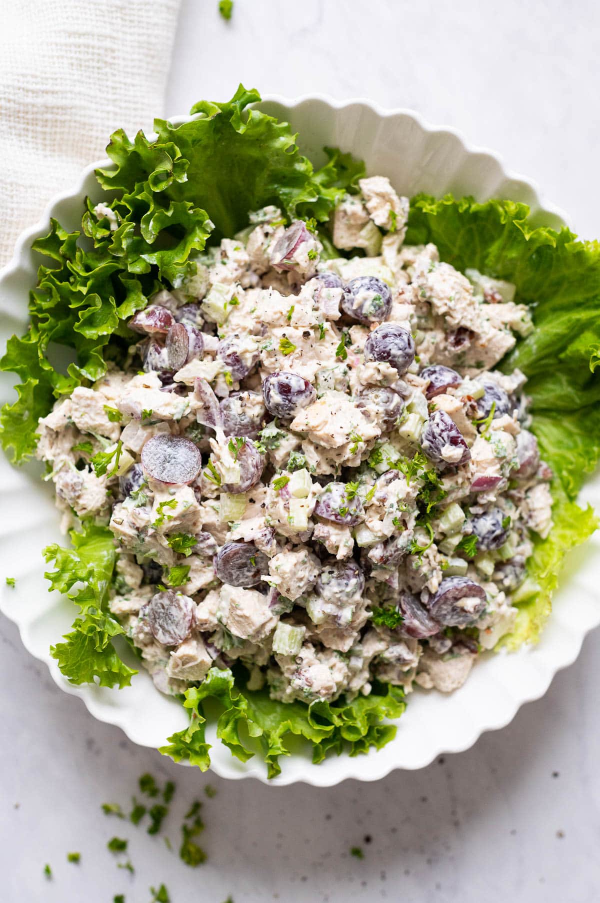 Classic chicken salad recipe served on a bed of lettuce leaves in a bowl.