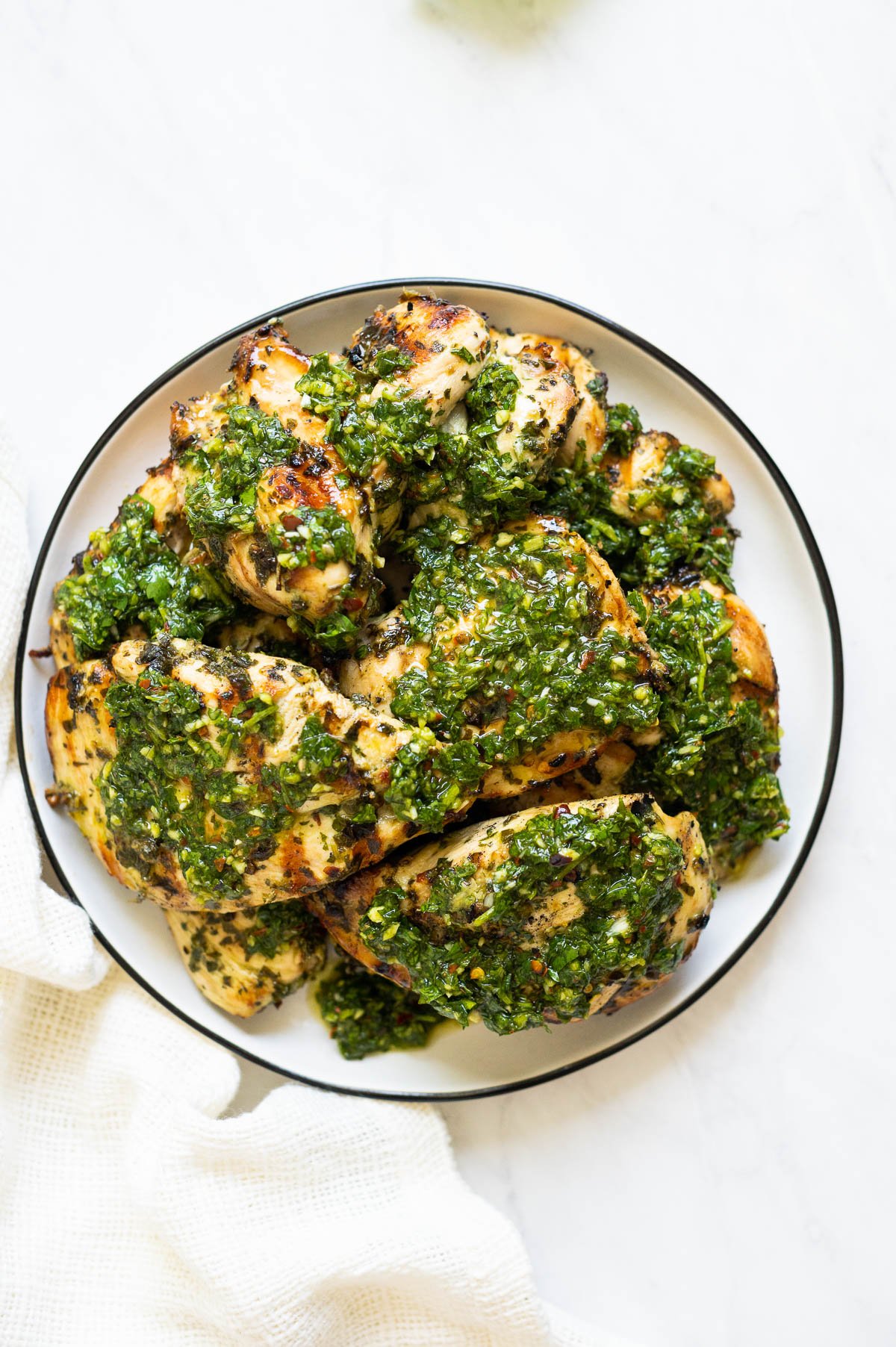 Chimichurri chicken served on a plate and linen napkin nearby.