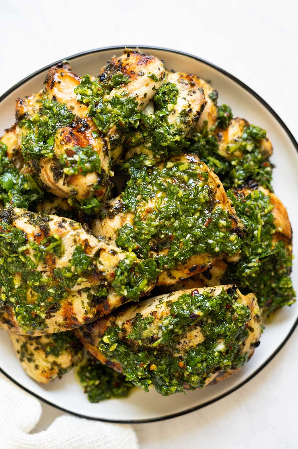 Chimichurri chicken thighs served with chimichurri sauce on a plate.