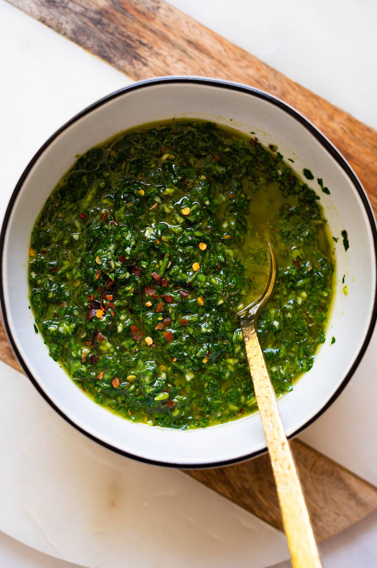 Chimichurri recipe in white bowl with a spoon.