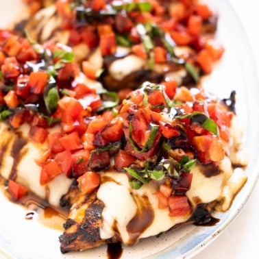 Bruschetta chicken drizzled with balsamic glaze and served on a platter.
