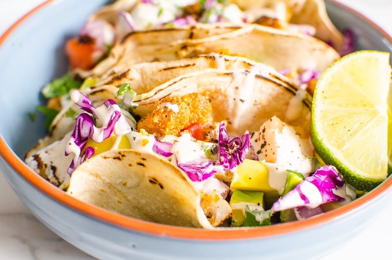 Fish tacos served with shredded cabbage and fish taco sauce in a bowl.
