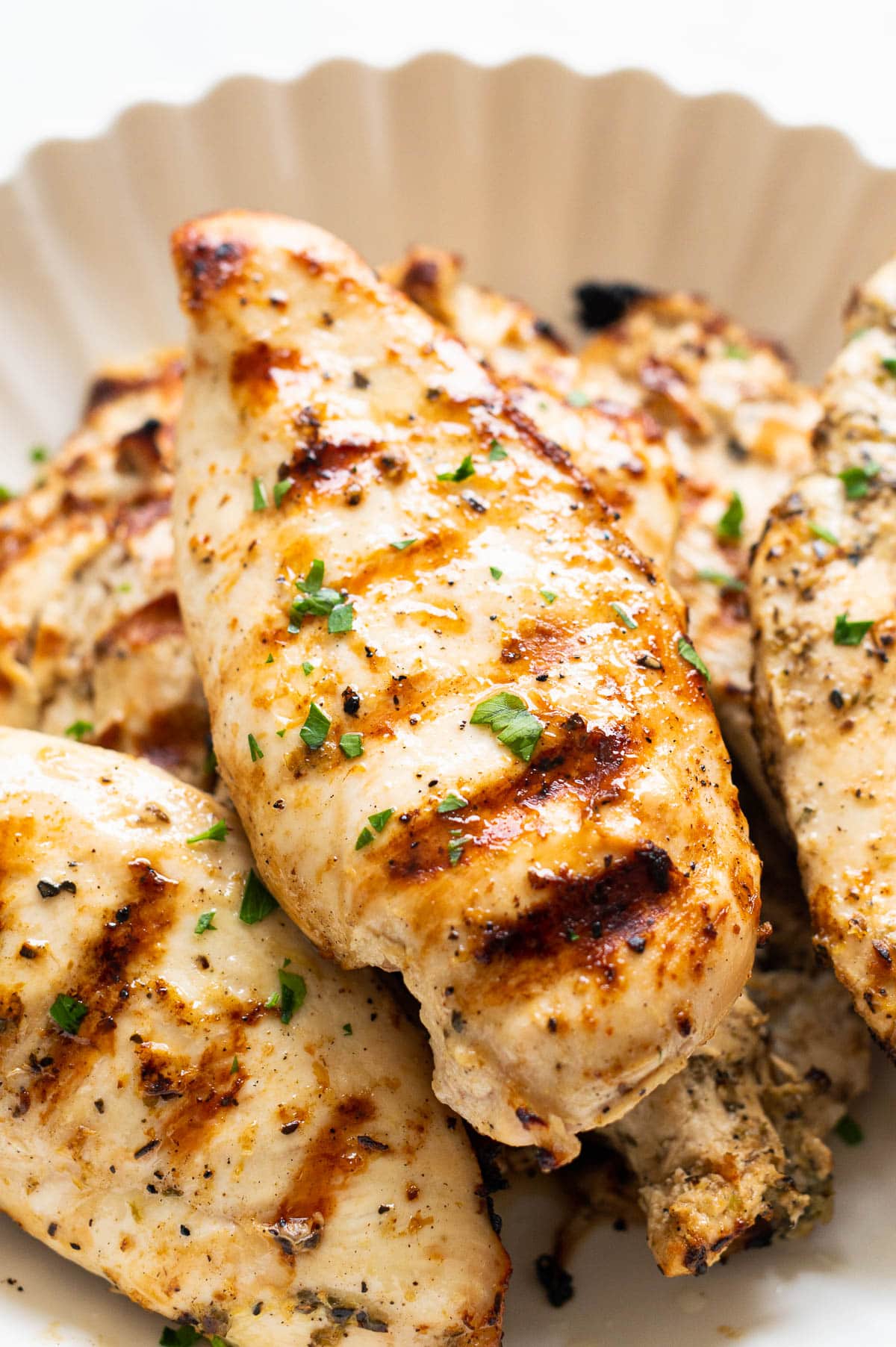 Grilled chicken breasts on a plate garnished with parsley.